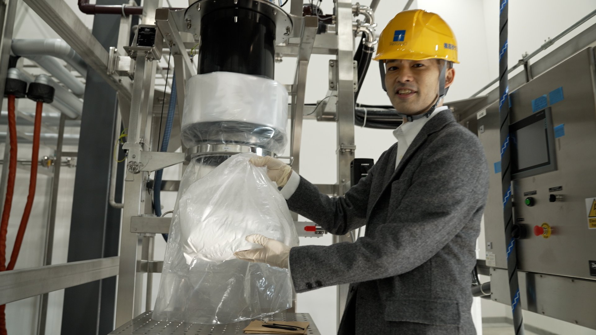 写真12 連続生産で生成した化合物を持つ鶴本さん (2).jpg