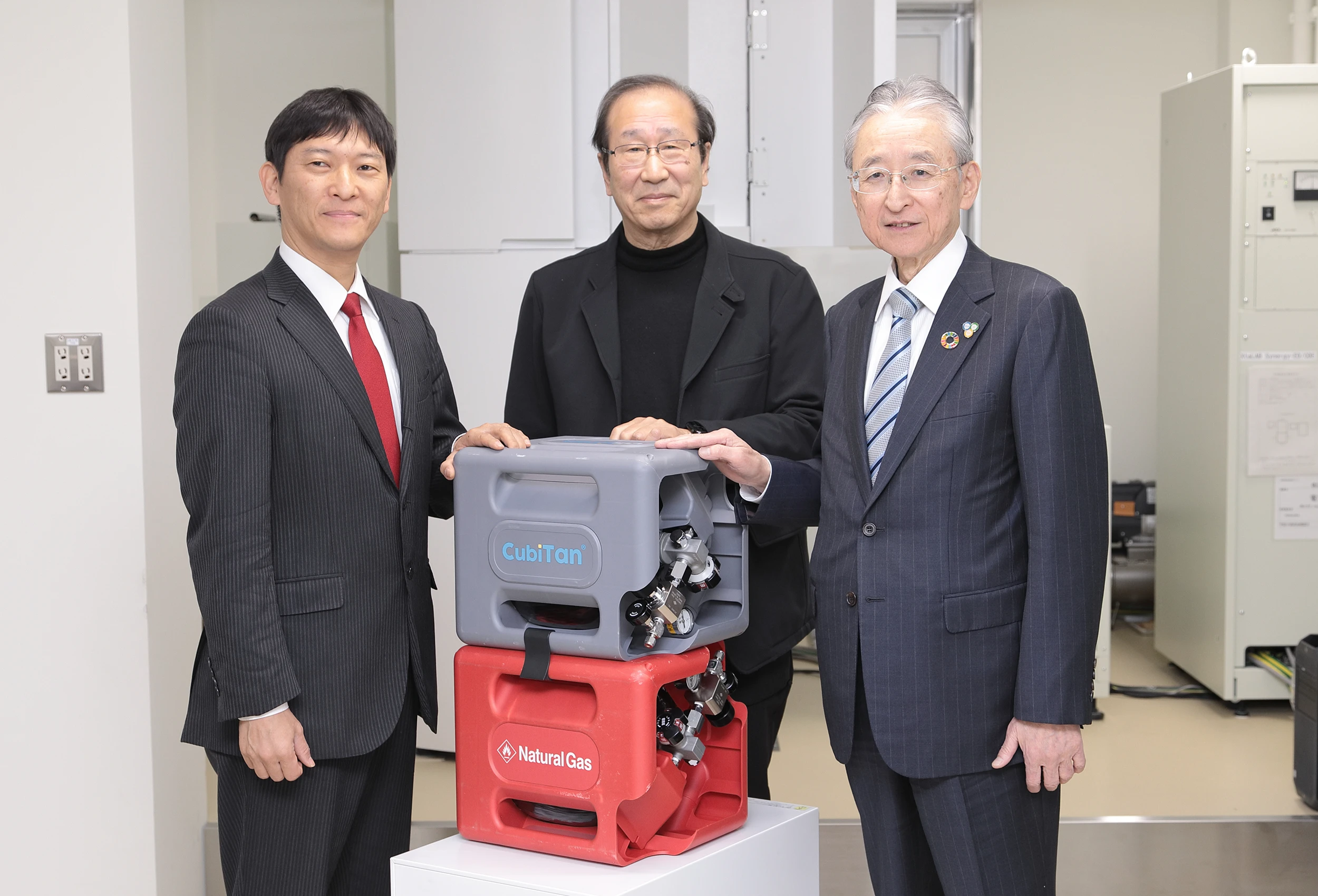左がAtomis社の創業者である樋口雅一氏。中央にあるのが、高圧ガス流通の運搬・コスト面における課題解決のために同社らが開発した次世代高圧ガス容器「CubiTan」。ガス吸着剤としてMOFを内蔵しており圧力を上げることなくガスを貯蔵できる
