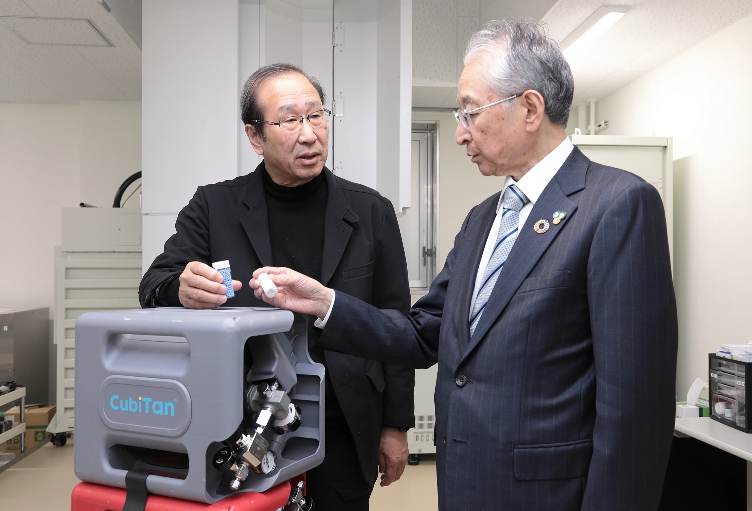 MOF材料が入った瓶を手にしながら語り合う北川氏と斎藤理事長